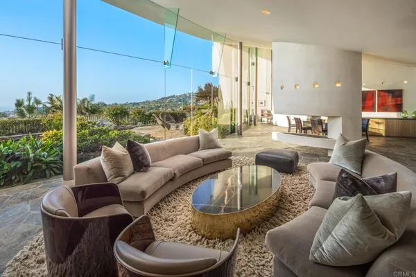 a living room with couches and kitchen view with wooden floor