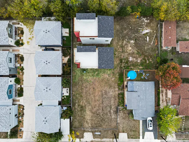 an aerial view of residential houses with outdoor space and parking