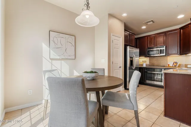 a kitchen with stainless steel appliances kitchen island granite countertop a dining table chairs and a refrigerator