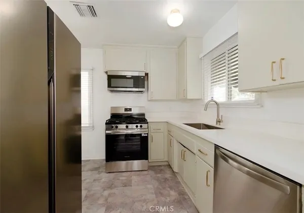 a kitchen with stainless steel appliances granite countertop a stove a sink and a refrigerator