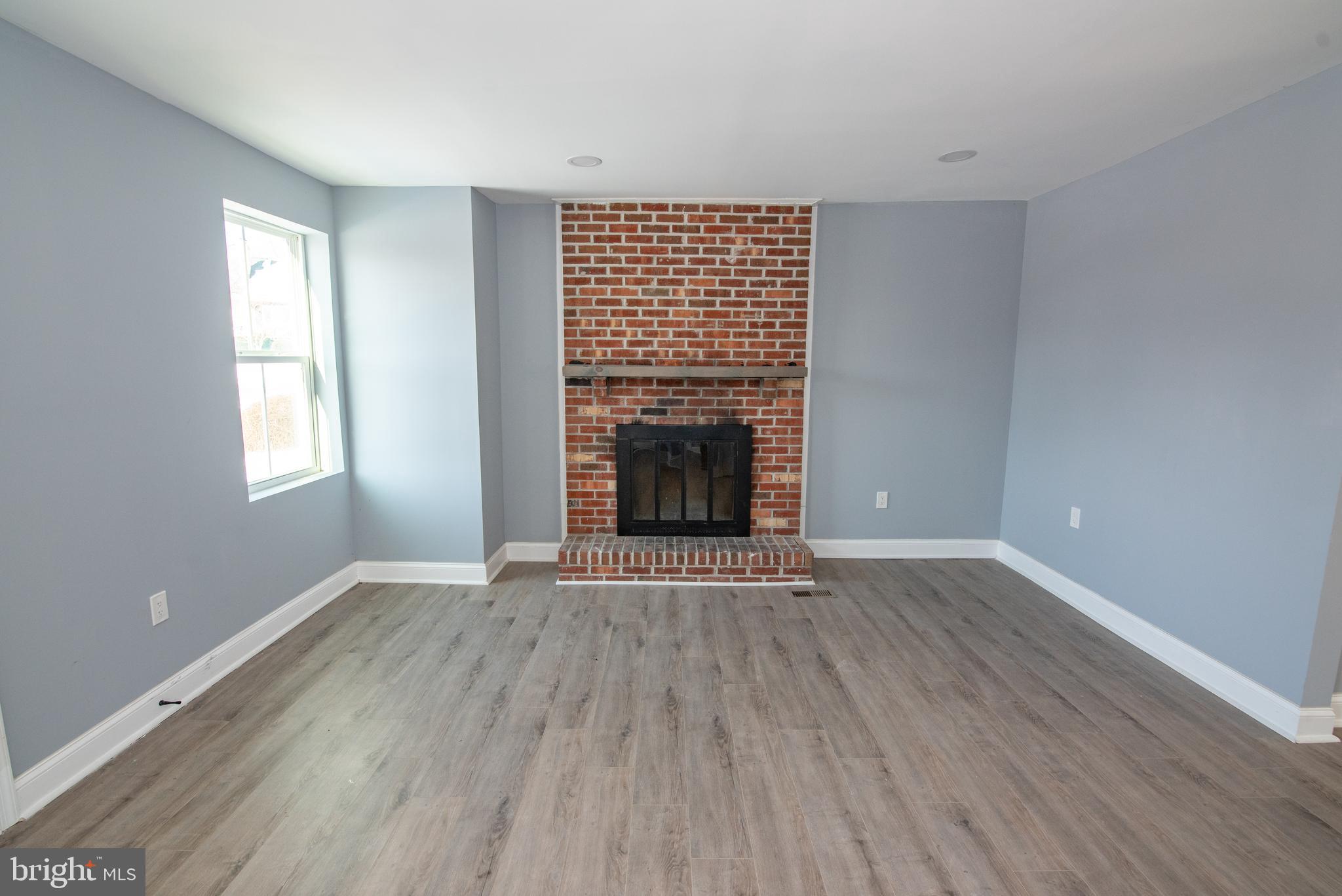 2900 Scherer Avenue Baltimore, MD 21234 - Photo 5 of 37 an empty room with wooden floor fireplace and windows