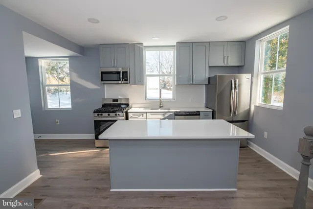 a kitchen with kitchen island a sink wooden floor and a window