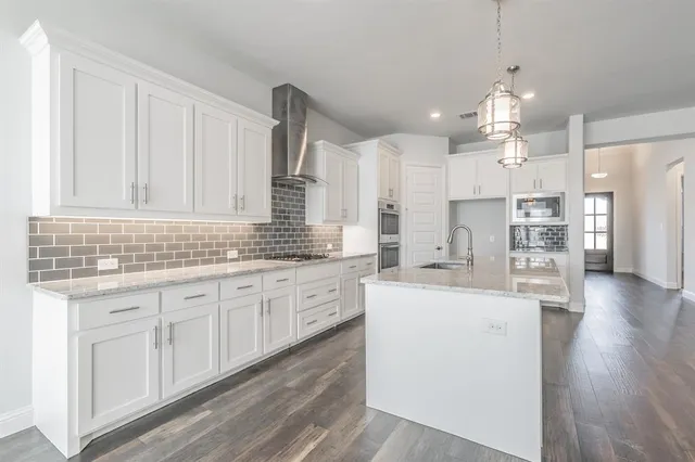 a kitchen with stainless steel appliances kitchen island granite countertop a stove a sink dishwasher and a refrigerator with wooden floor