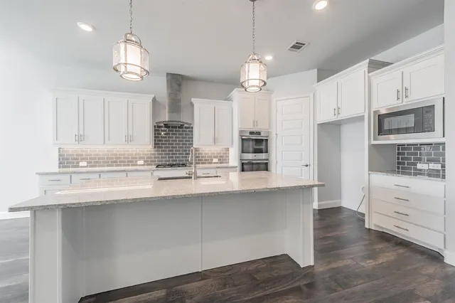 a kitchen with stainless steel appliances kitchen island granite countertop a stove a sink and a refrigerator
