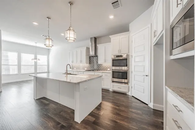 a large kitchen with stainless steel appliances granite countertop a lot of counter space and wooden floors
