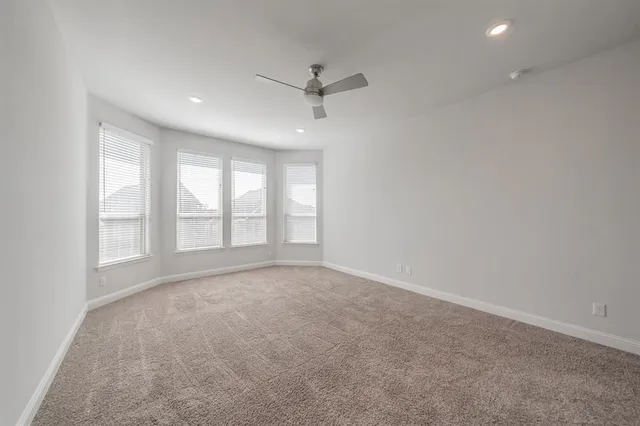 an empty room with windows and ceiling fan