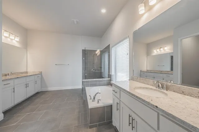 a bathroom with a granite countertop double vanity sink a mirror and a bathtub
