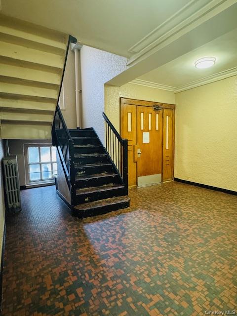 48-20 44th Street, Unit 4C Queens, NY 11377 - Photo 2 of 12 Staircase featuring a textured wall, radiator, carpet, and ornamental molding