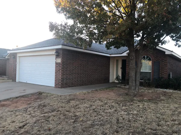 a front view of house with yard and trees in the background