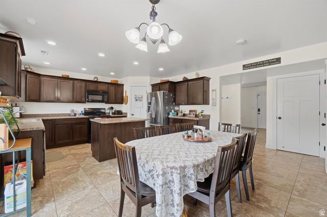 592 West 650 South Springville, UT 84663 - Photo 10 of 33 Spacious kitchen with a central dining area, featuring extensive dark wood cabinetry, granite-style countertops, stainless steel appliances, and large format tile flooring