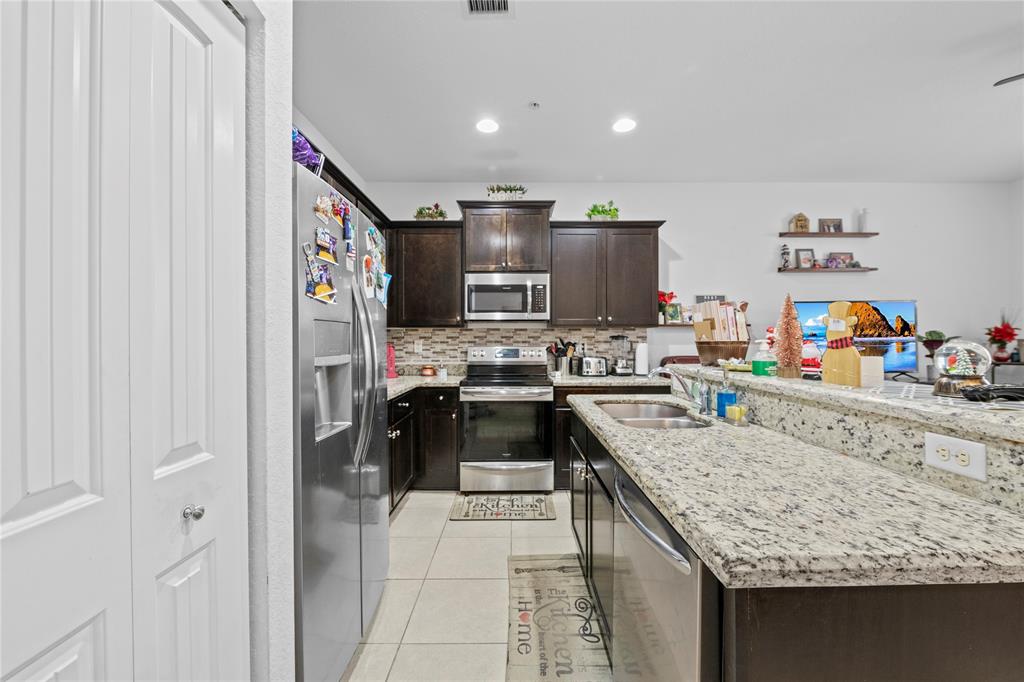 197 Southwest 6th Place, Unit 197 Pompano Beach, FL 33060 - Photo 9 of 25 a kitchen with stainless steel appliances granite countertop a sink stove and refrigerator