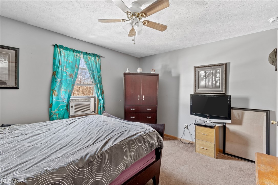 4330 Lunar Road Northwest Minerva, OH 44657 - Photo 9 of 21 Bedroom with ceiling fan, light colored carpet, and a textured ceiling
