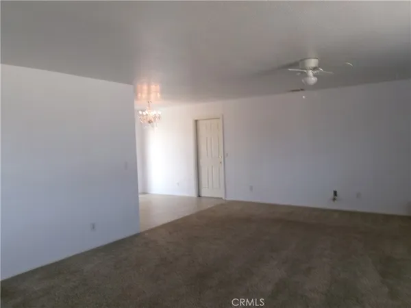 an empty room with an entryway and chandelier fan
