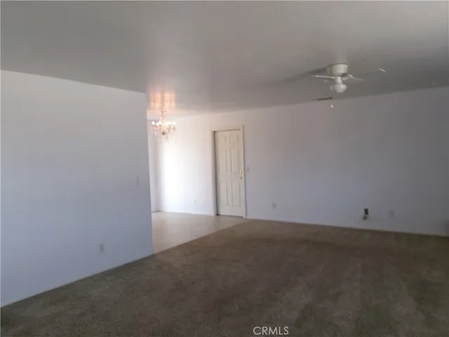an empty room with an entryway and chandelier fan