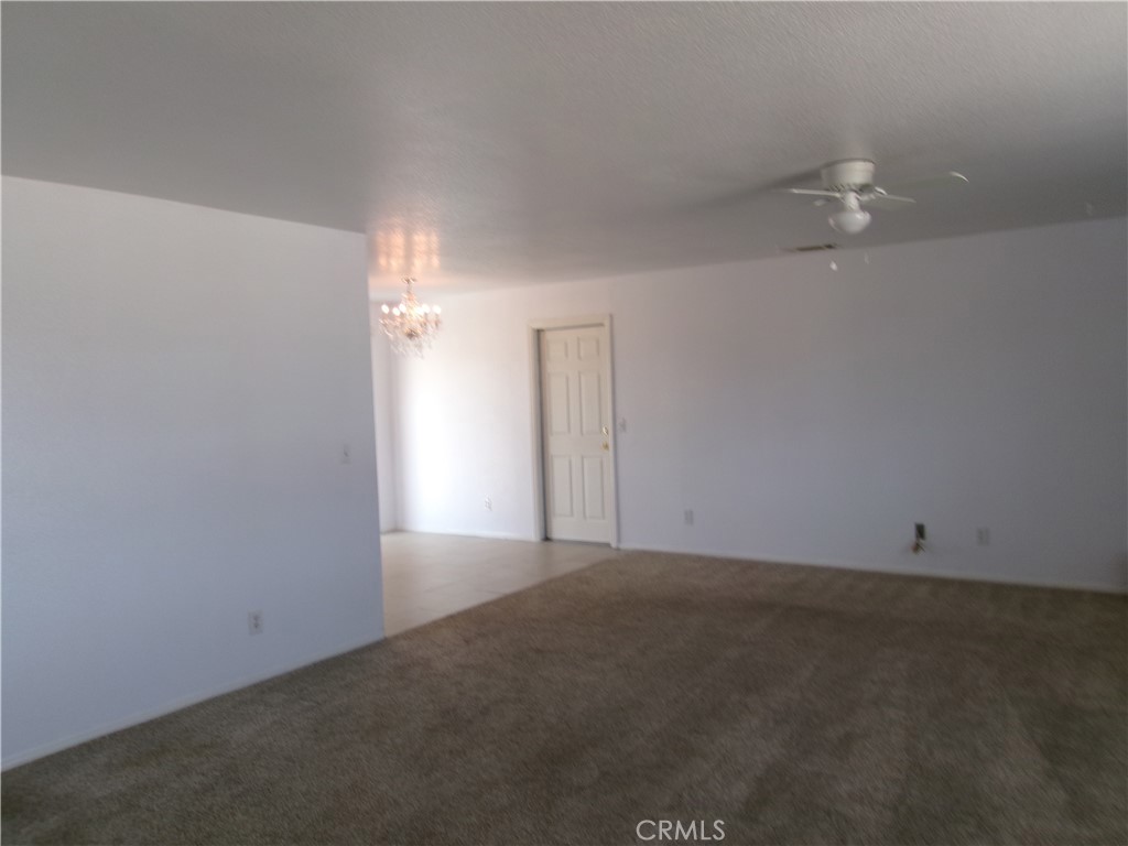 14936 Central Road Apple Valley, CA 92307 - Photo 17 of 33 an empty room with an entryway and chandelier fan
