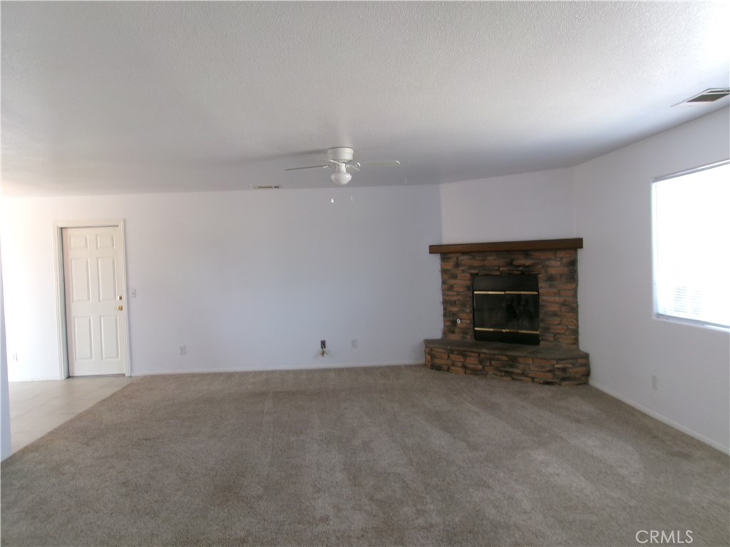 14936 Central Road Apple Valley, CA 92307 - Photo 19 of 33 an empty room with a fireplace and window