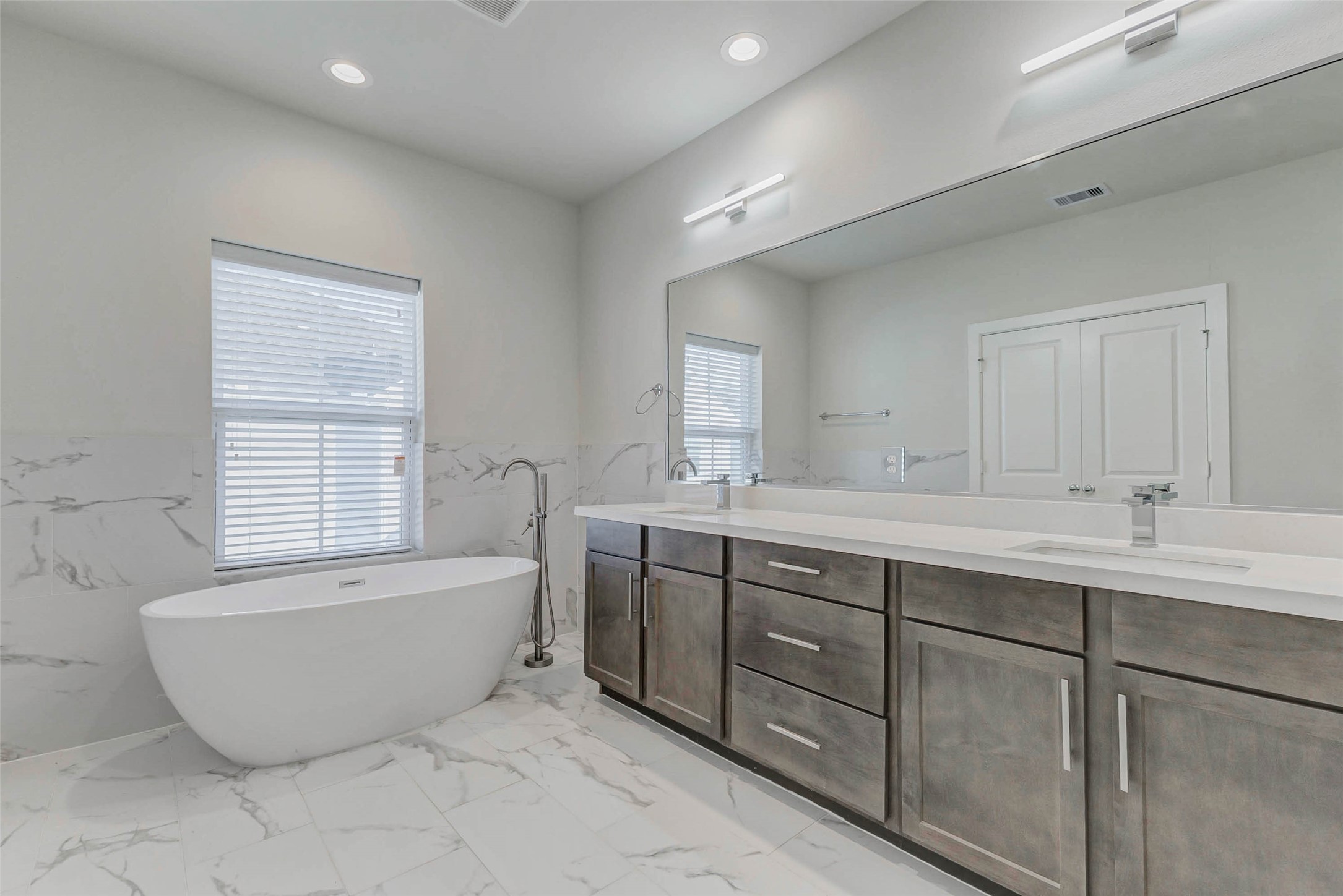 6313 Nelson Falls Lane Houston, TX 77008 - Photo 22 of 34 a bathroom with a tub a double vanity sink a mirror and a window