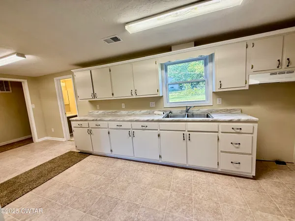 a kitchen with granite countertop white cabinets white stainless steel appliances and sink