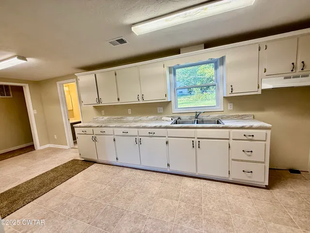 a kitchen with granite countertop white cabinets white stainless steel appliances and sink
