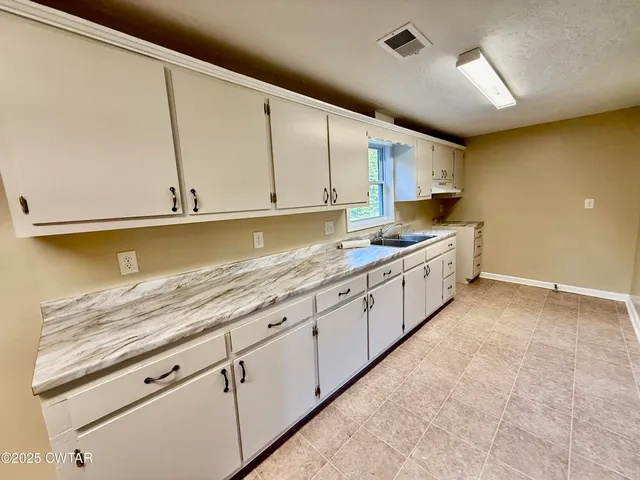 a kitchen with granite countertop a sink and cabinets