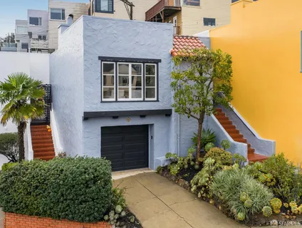 a front view of a house with a yard and potted plants