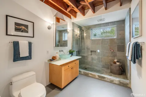 a bathroom with a granite countertop sink a toilet and shower