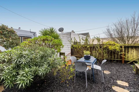 a patio with table and chairs and potted plants