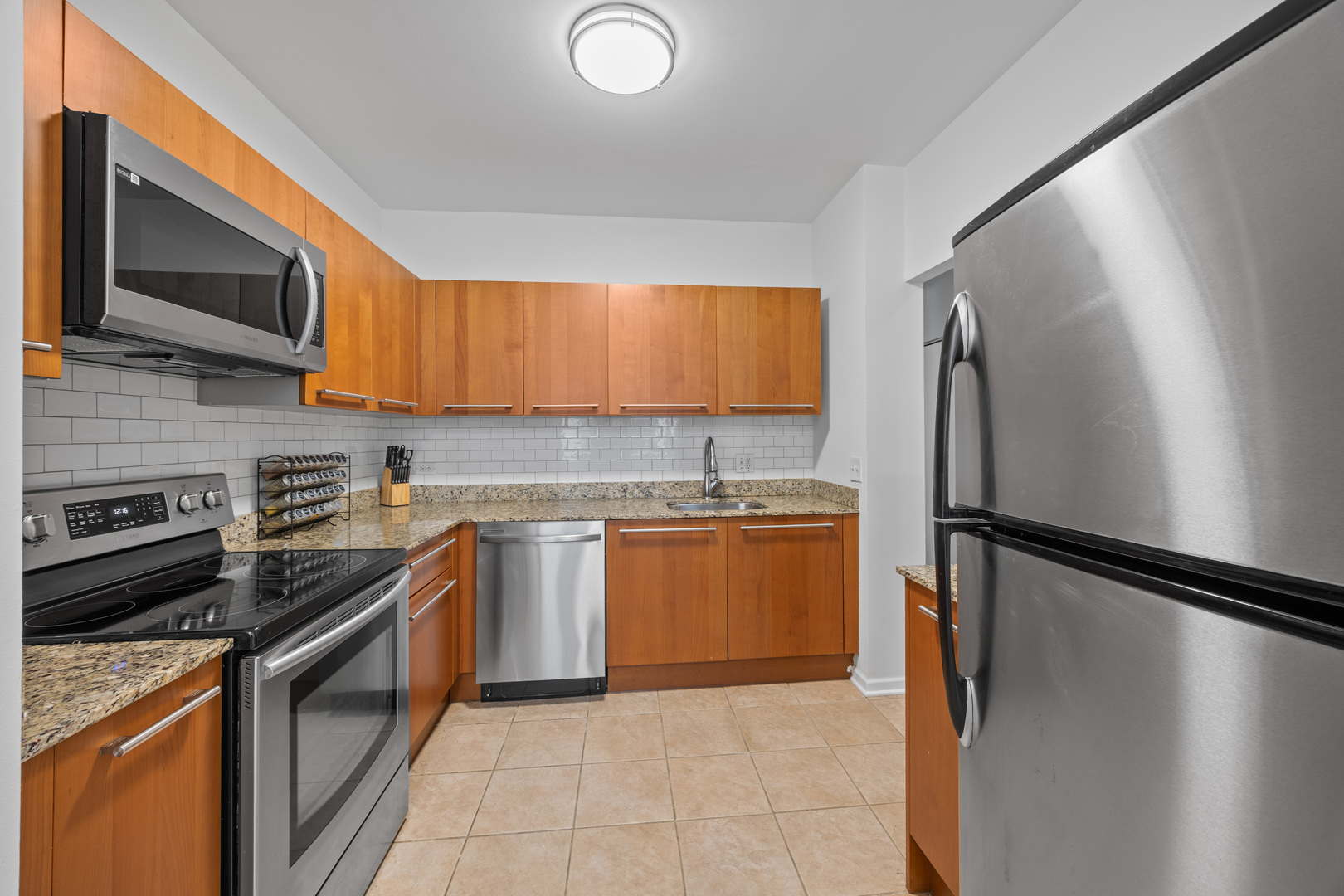 740 South Federal Street, Unit 710 Chicago, IL 60605 - Photo 11 of 23 a kitchen with stainless steel appliances granite countertop a stove top oven a sink and a refrigerator
