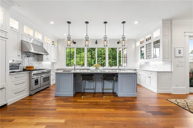 a kitchen with stainless steel appliances granite countertop a stove a sink and a wooden floors
