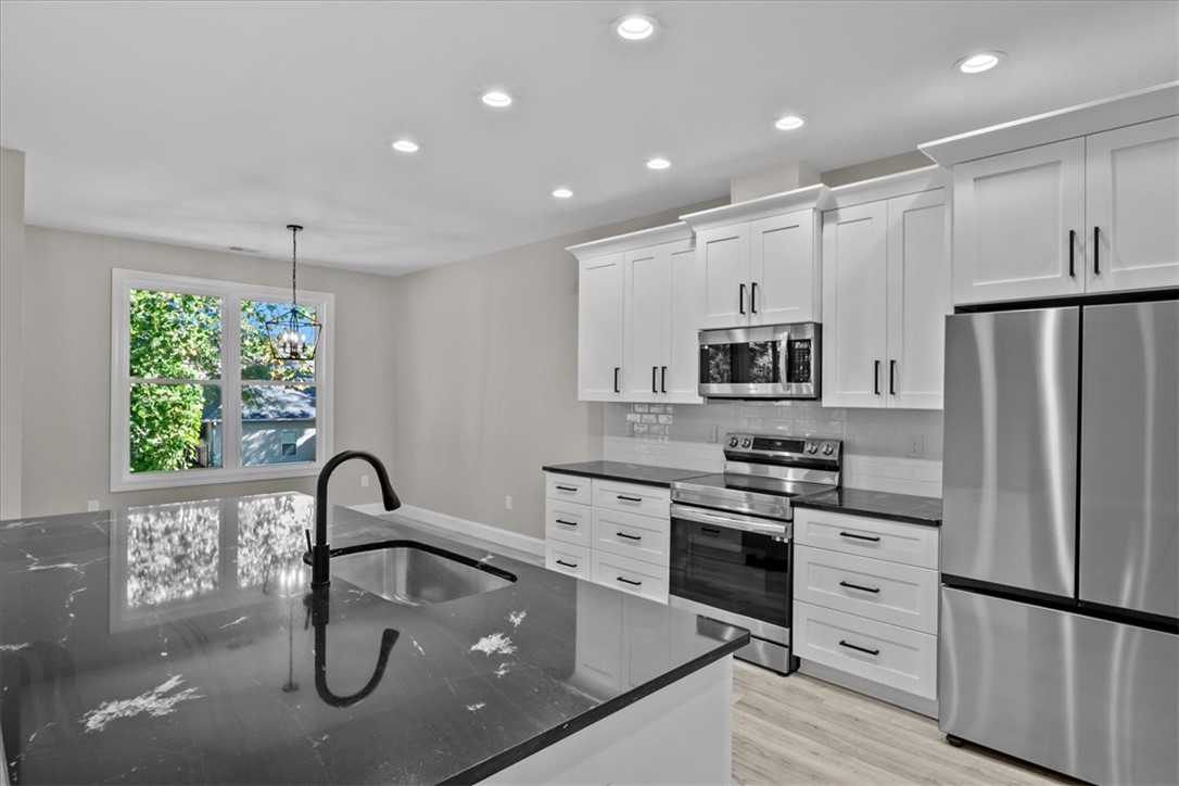105 Bree Drive Anderson, SC 29621 - Photo 12 of 48 Modern kitchen with sleek black countertops and pristine white cabinetry awaits your culinary adventures.