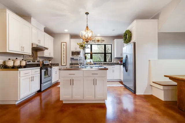 a kitchen with stainless steel appliances a white stove top oven cabinets and a large window