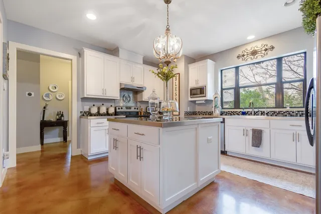 a kitchen with stainless steel appliances granite countertop a stove oven a sink dishwasher and white cabinets with wooden floor