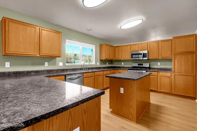 a kitchen with stainless steel appliances granite countertop a stove a sink a microwave and a refrigerator