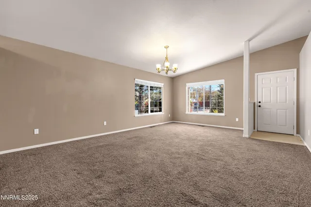 an empty room with chandelier fan and windows