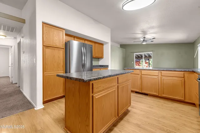 a kitchen with granite countertop a refrigerator a sink and white cabinets