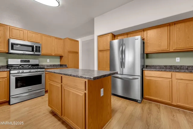 a kitchen with stainless steel appliances granite countertop a refrigerator a stove and a sink with wooden floor