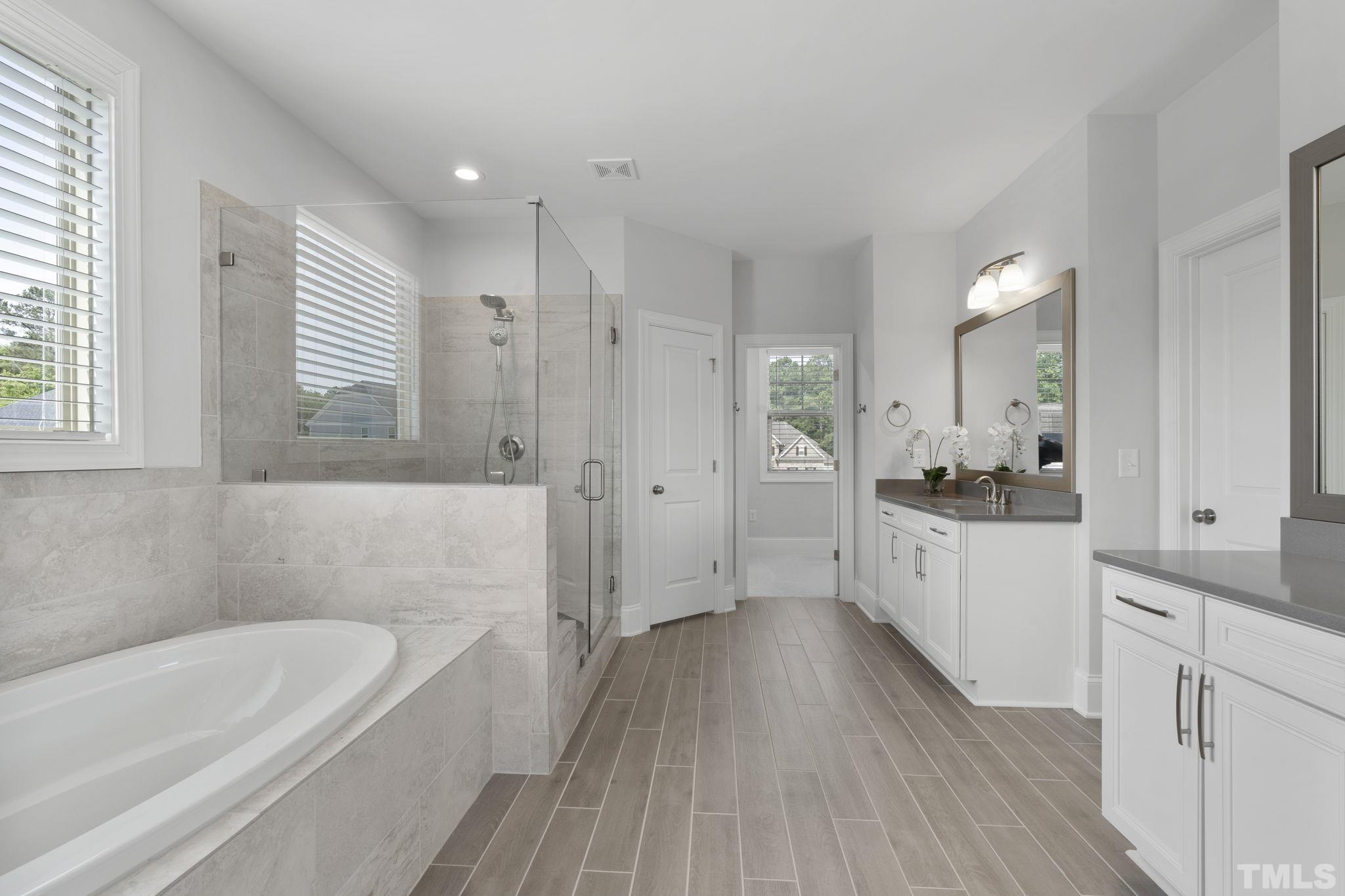 3157 Beechcroft Lane Apex, NC 27502 - Photo 25 of 42 a bathroom with a bathtub a sink a vanity and a shower