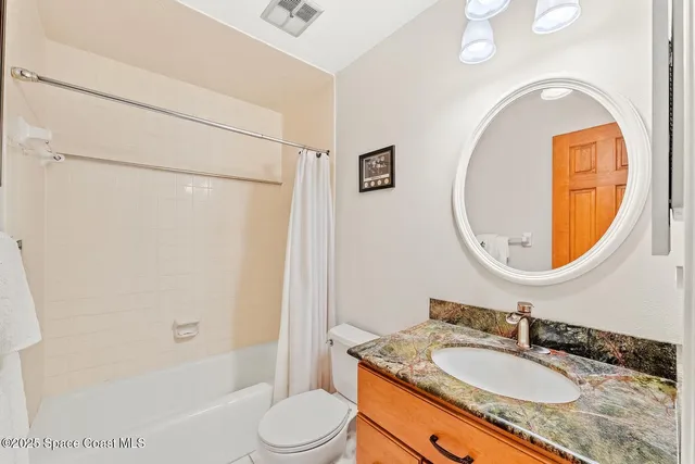 a bathroom with a granite countertop sink mirror toilet and bathtub