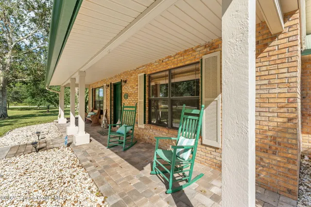 a porch with a table and chairs and potted plants