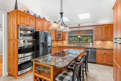 a kitchen with stainless steel appliances a stove top oven refrigerator and a sink