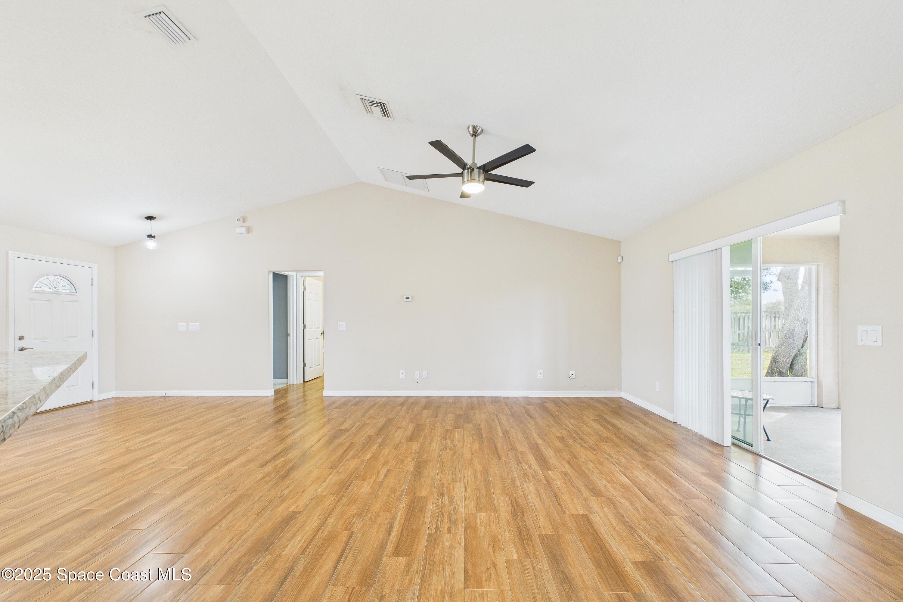 1936 Gloria Circle Palm Bay, FL 32905 - Photo 7 of 50 a view of a big room with wooden floor and a ceiling fan