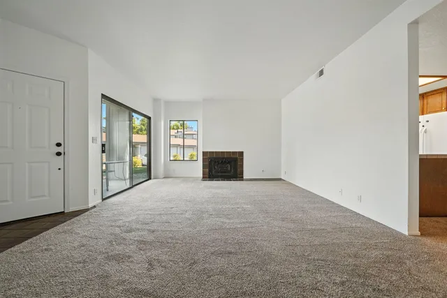 a view of an empty room with a fireplace and a window