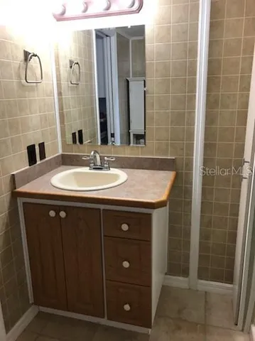 a bathroom with a granite countertop sink a toilet a mirror and shower