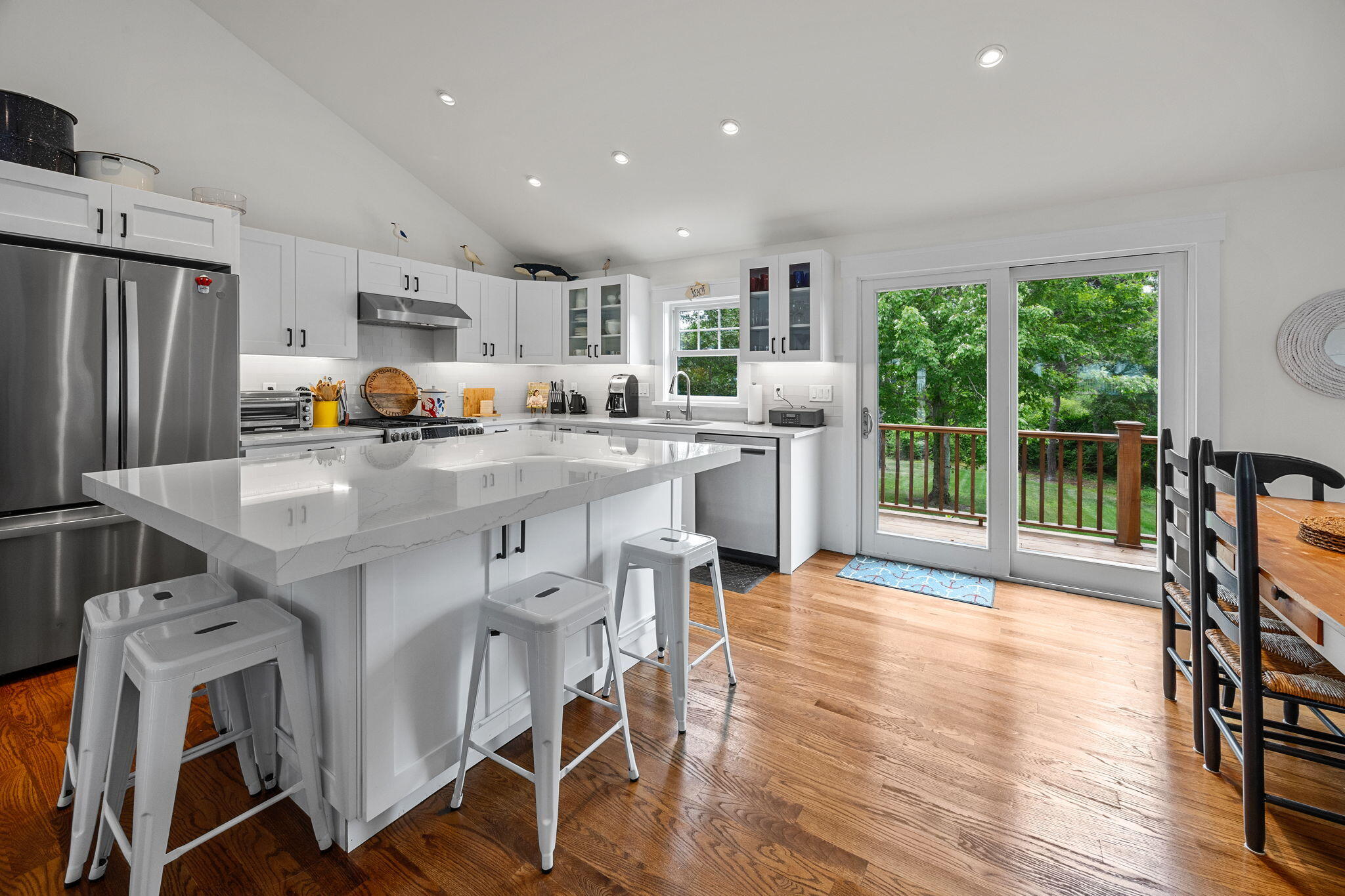 93 Orleans Road Chatham, MA 02633 - Photo 15 of 48 a open kitchen with stainless steel appliances granite countertop a stove top oven a refrigerator a dining table and chairs with wooden floor