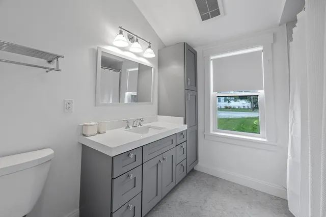 a bathroom with a toilet a sink a mirror and a window