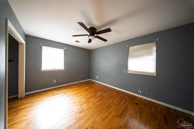 a view of a big room with windows and ceiling fan