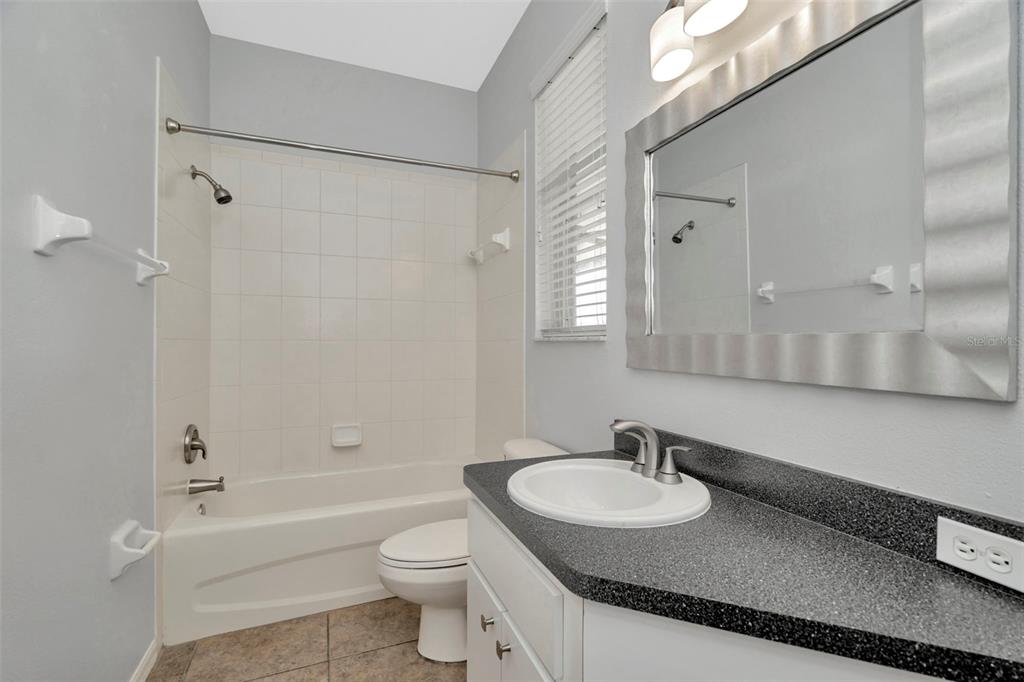 8918 Linebrook Drive Trinity, FL 34655 - Photo 42 of 50 a bathroom with a granite countertop sink a toilet a mirror and shower