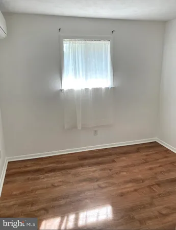 a view of an empty room with wooden floor and window