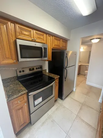a kitchen with granite countertop a refrigerator and a stove top oven