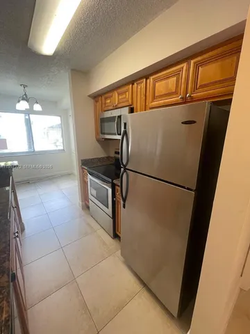 a view of a refrigerator in kitchen and an empty room